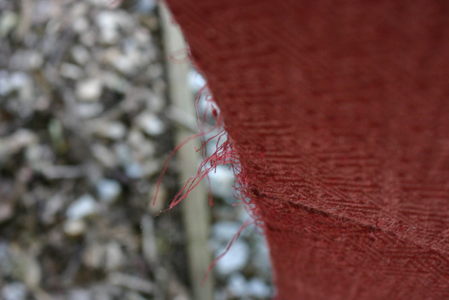 loose threads on back of maroon upholstered armchair