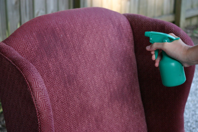 spray bottle misting fabric on armchair before painting