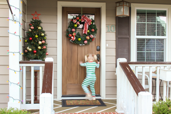 Toddler Girl Opening Wood Front Door at Christmas