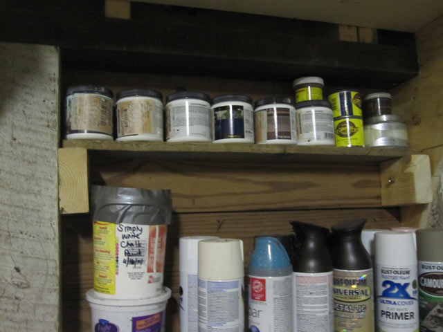 Shelf between studs holding paint and stain sample cans