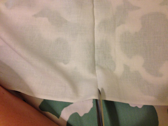 scissors cutting white fabric in fold