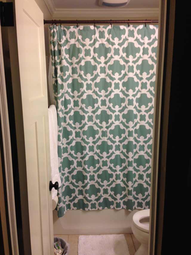 Blue shower curtain hanging near ceiling in tiny bathroom