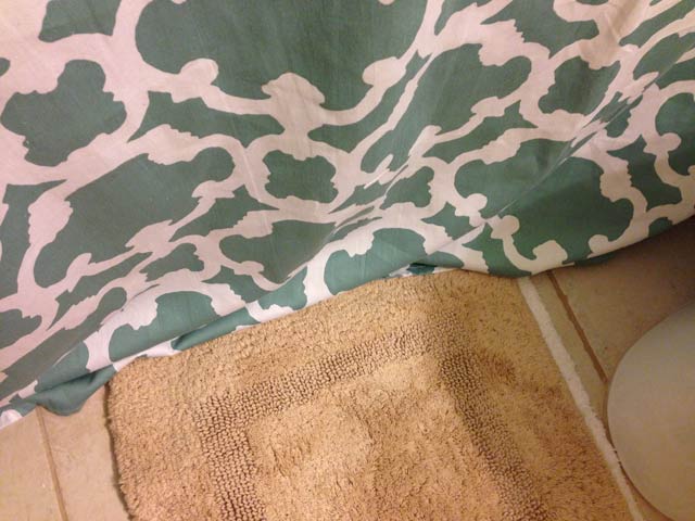 shower curtain puddled on bathroom floor