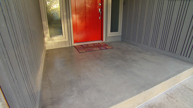 grey concrete stain on front porch next to grey siding and red entry door
