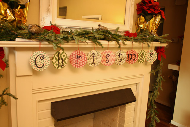 DVDs wrapped in scrapbook paper hanging from mantel to spell Christmas with red poinsettias douglas fir garland