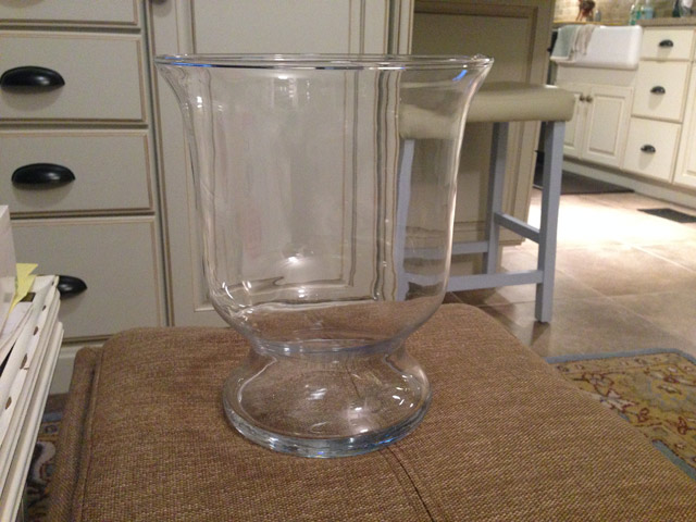 empty glass vase sitting on tan ottoman in sunroom