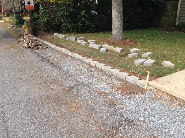 first run of block retaining wall laid out at gravel parking strip