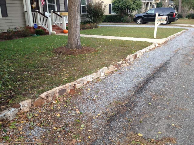 small retaining wall in front of vinyl siding house and asphalt street