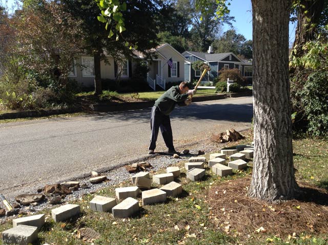 Brandon swinging sledge hammer to tear out old retaining wall