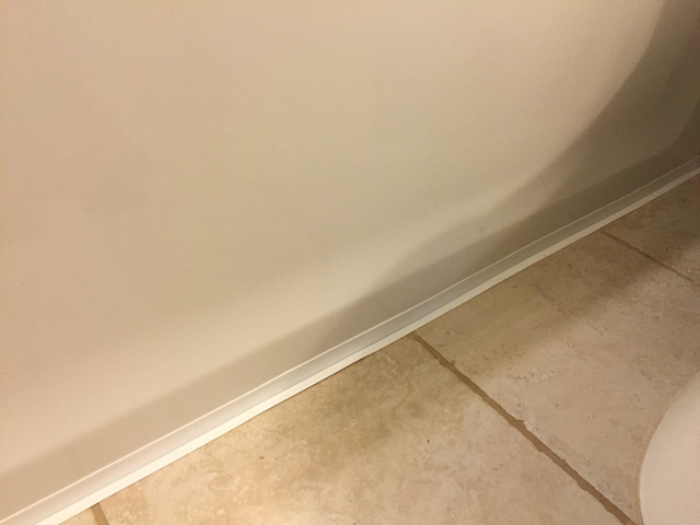 homax caulk strip installed on white bathtub at tan tile
