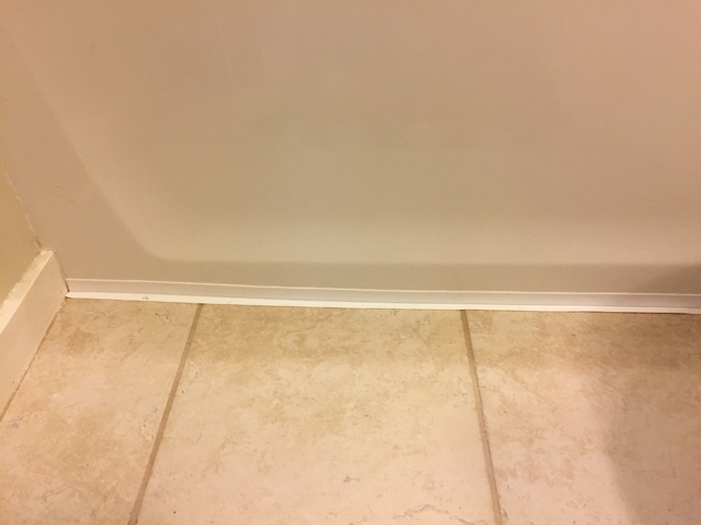 Homax caulk strip installed at base of white bathtub and tan tile floor