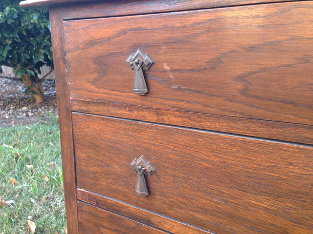 dingy, dirty drawer pulls hardware on stained wood dresser