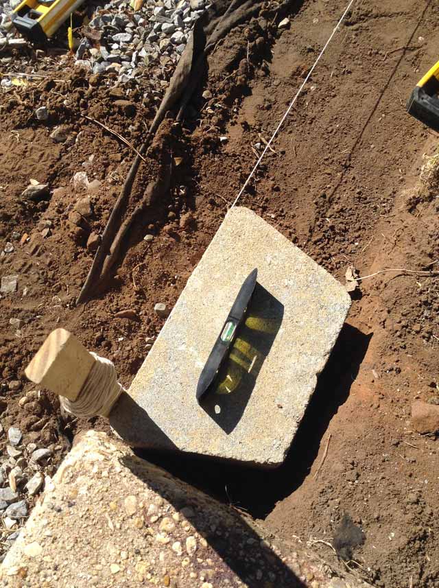 grey concrete block in dirt with small torpedo level on top