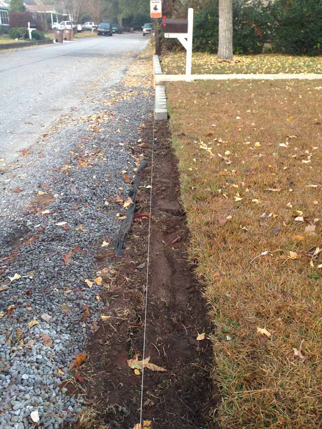 dirt ready for retaining wall blocks in front of dormant grass
