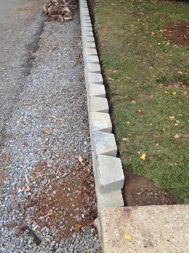 side view of pavestone retaining wall in place by concrete sidewalk