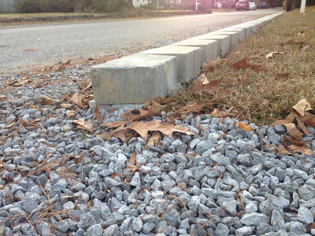 backside of retaining wall at grass and gravel driveway