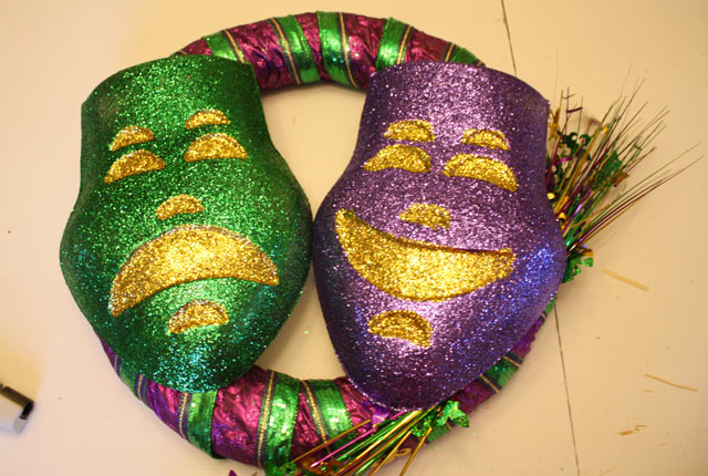 Mardi Gras face masks glued to ribbon-wrapped wreath sitting on dining room table