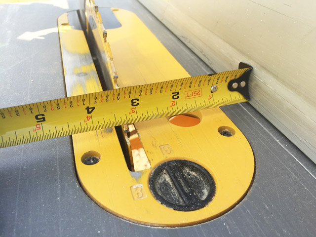 yellow tape measure sitting on yellow table saw measuring 3 and quarter inches