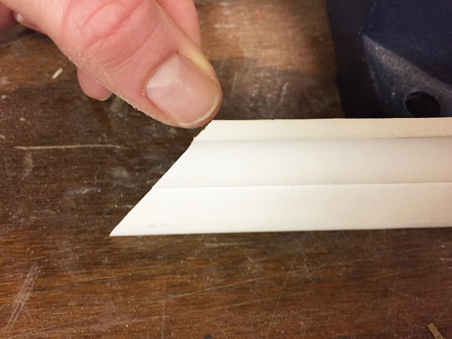 thumb pointing at corner edge of bed molding sitting on workbench