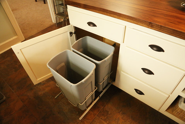 gray trash can pull outs in white kitchen cabinet 