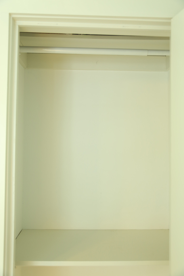 empty white closet with white clothing rod