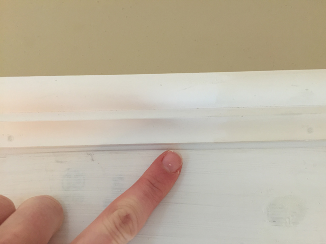 finger pointing at caulk under bed molding