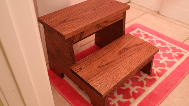 Stained oak step stool on workbench in shop.