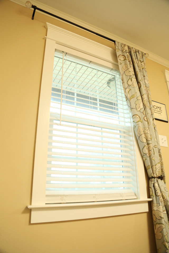 white faux wood blinds hanging in window with craftsman trim