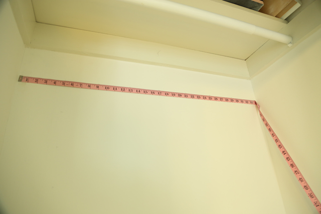 pink sewing measuring tape taped to white closet wall