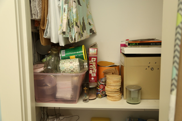 collection of glass jars in pink bin on shelf of white craft closet