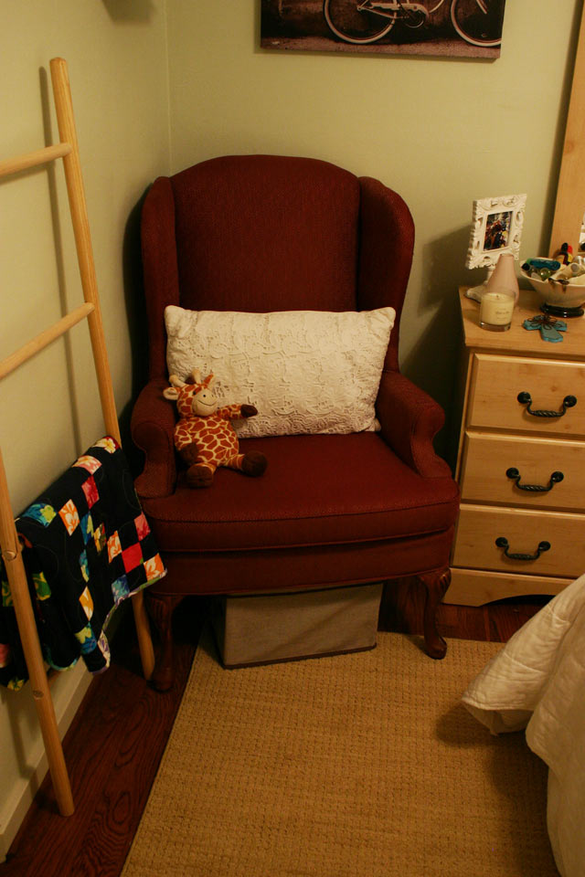 maroon club side chair with white pillow and giraffe stuffed animal