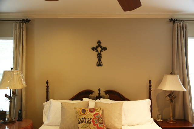 metal cross hung above white king-sized bed