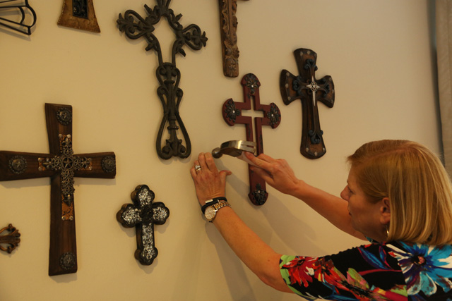 hanging metal and wood crosses on drywall bedroom wall