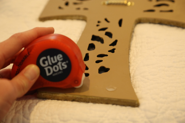 applying repositionable glue dots to back of cross