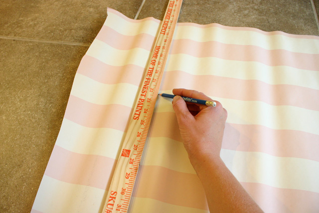 using x-acto knife to cut wallpaper along yardstick