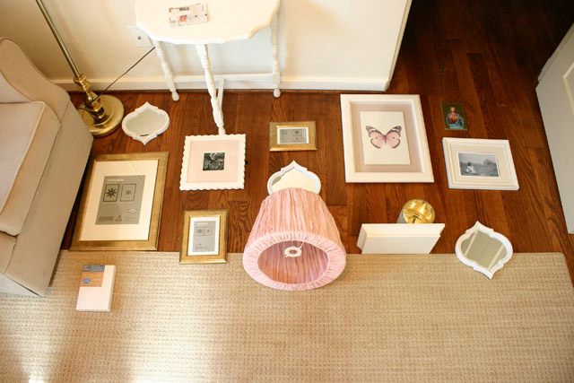 white and gold frames with pink lamp shade gallery wall on floor