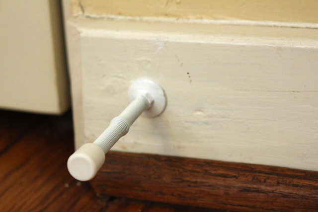 white door stopper in white baseboard with stained hardwood floors