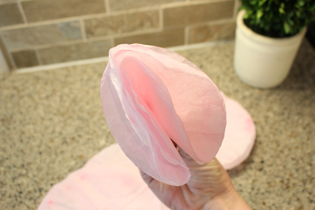 folding pink coffee filter in half to make paper flowers