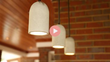 concrete pendant lights hanging over bar in brick outdoor kitchen