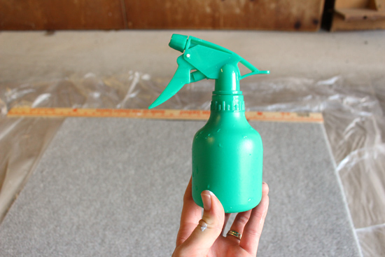 small green spray bottle held by white hand