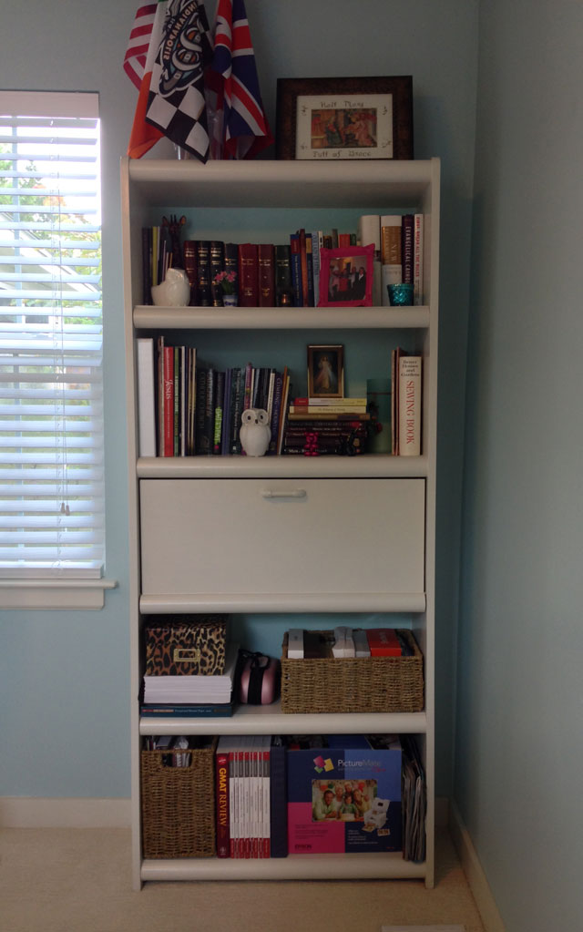 organized white bookshelf with baskets and picture frames